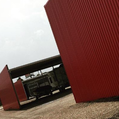 The red aluminum siding of Countryside Trailer Sales' storage facility with a camper in the …