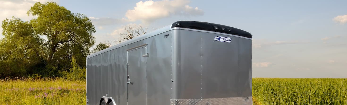 An enclosed Continental Cargo trailer that's parked on a the farm land